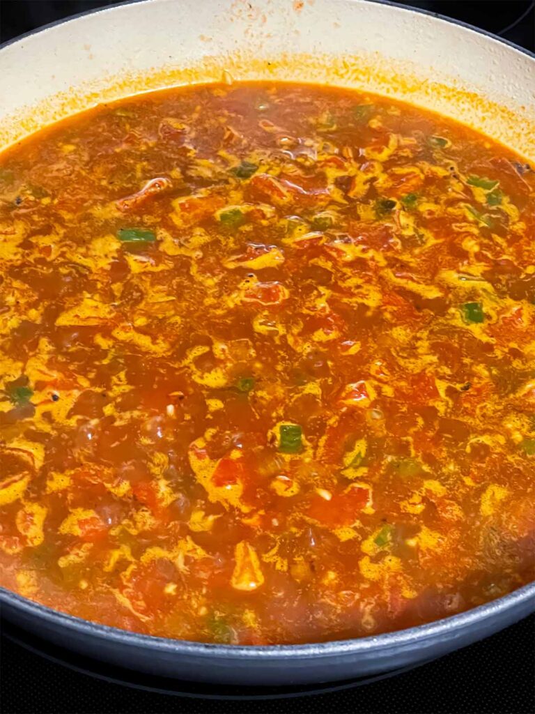 Spanish rice ingredients simmering in a skillet.