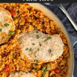 Spanish pork chops and rice garnished with chopped parsley in a light colored skillet.