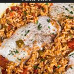 Spanish pork chops and rice garnished with chopped parsley in a light colored skillet.