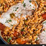 Spanish pork chops and rice garnished with chopped parsley in a light colored skillet.