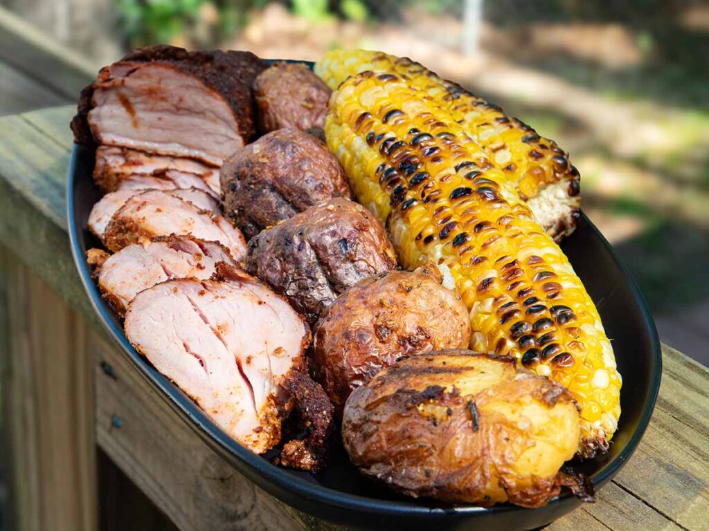 Smoked pork tenderloin with grilled corn and potatoes.