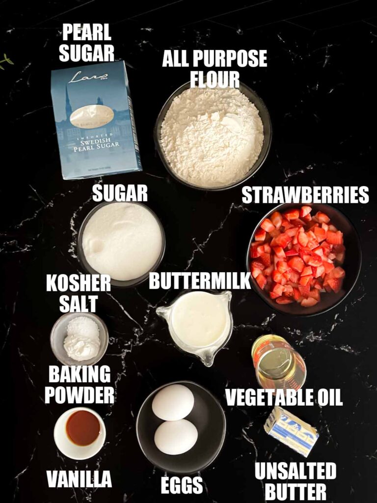 Strawberry muffin recipe ingredients on a dark surface.