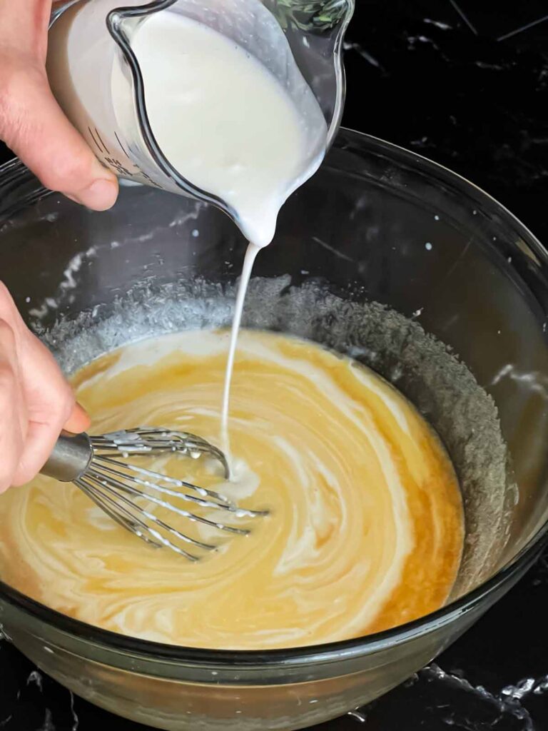 Buttermilk being added to the wet ingredients for strawberry muffins.