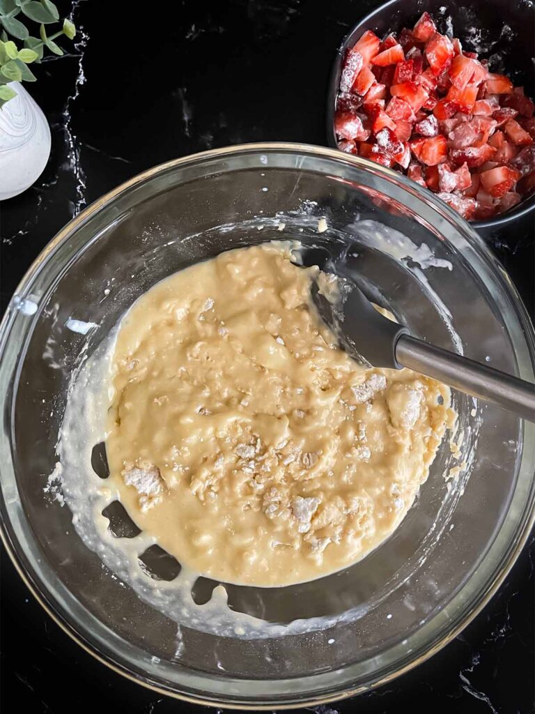 Strawberry muffin batter mixed in a glass bowl.