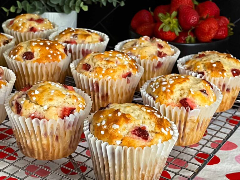 Strawberry muffins on a wire cooling rack on a dark surface.