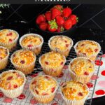 Strawberry muffins on a wire cooling rack on a dark surface.