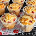 Strawberry muffins on a wire cooling rack on a dark surface.