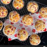 Strawberry muffins on a wire cooling rack on a dark surface.