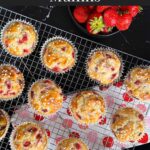 Strawberry muffins on a wire cooling rack on a dark surface.