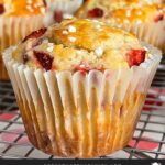 Strawberry muffins on a wire cooling rack on a dark surface.