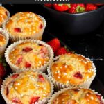 Strawberry muffins on an oval dark plate on a dark surface garnished with fresh whole strawberries.