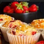 Strawberry muffins on an oval dark plate on a dark surface garnished with fresh whole strawberries.