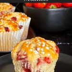 A strawberry muffin on a dark plate on a dark surface.