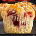 A strawberry muffin on a dark plate on a dark surface.