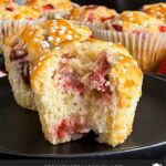 Two strawberry muffins on a dark plate on a dark surface.