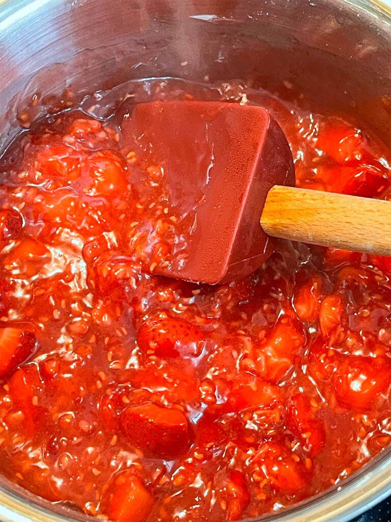 Thickened red berry filling in a metal saucepan for the berry poke cake recipe.