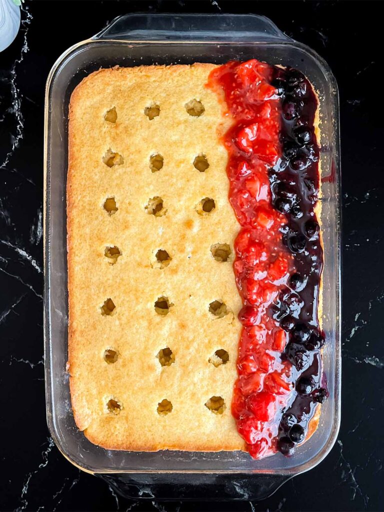 Strips of blueberry filling and red berry filling spooned into the poke cake.