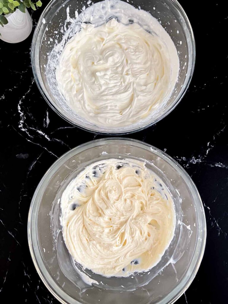 Whipped cream in a glass bowl and whipped cream cheese in another glass bowl.