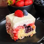 A slice of berry poke cake on a dark plate.