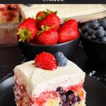 A slice of berry poke cake on a dark plate.