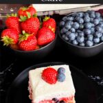 A slice of berry poke cake on a dark plate.