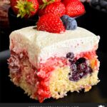 A slice of berry poke cake on a dark plate.