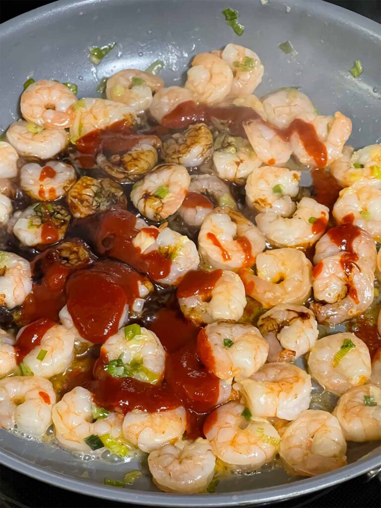 Cooked shrimp in a skillet with a gochujang mix of spices added.