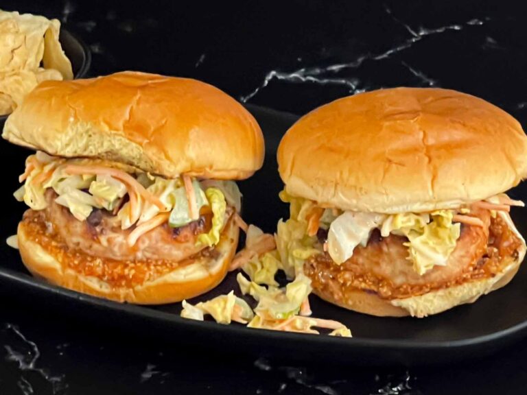 Grilled Carolina chicken burgers on a black plate.