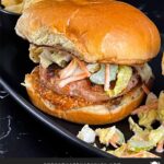 Carolina Grilled Chicken Burger on a black plate with potato chips.