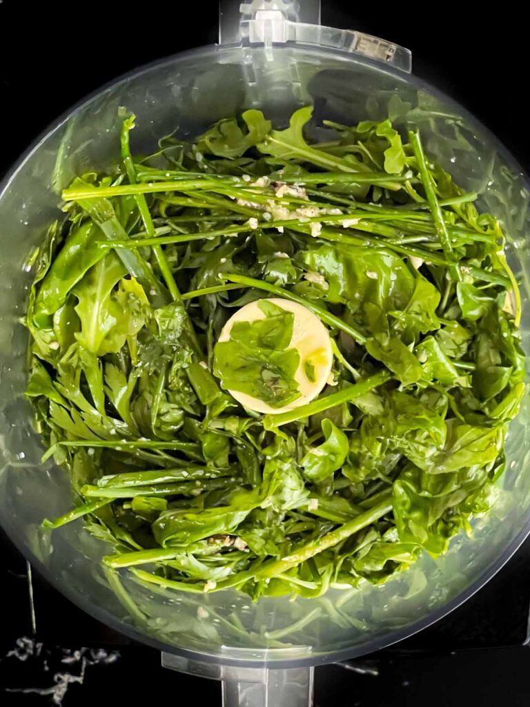 Herb vinaigrette ingredients in the bowl of a large food processor.