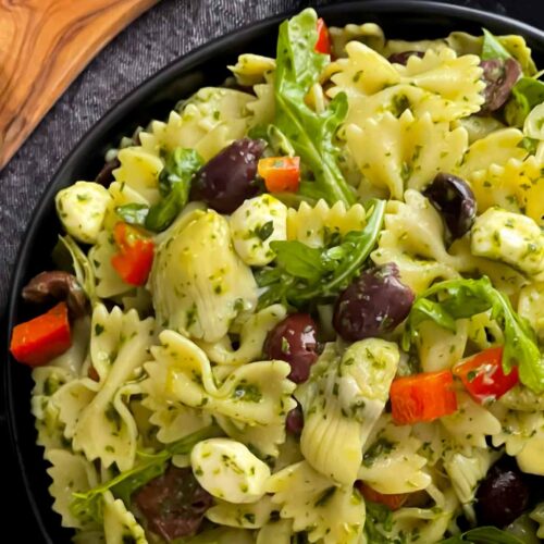 Mediterranean pasta salad in a dark bowl on a dark surface.