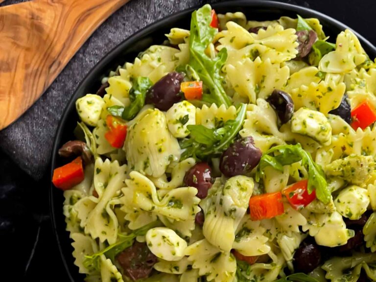 Mediterranean pasta salad in a dark bowl on a dark surface.