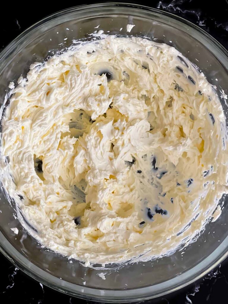 The cream cheese for the olive cheese ball beaten until smooth and creamy in a glass mixing bowl.