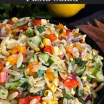 Orzo pasta salad in a dark bowl on a dark surface.