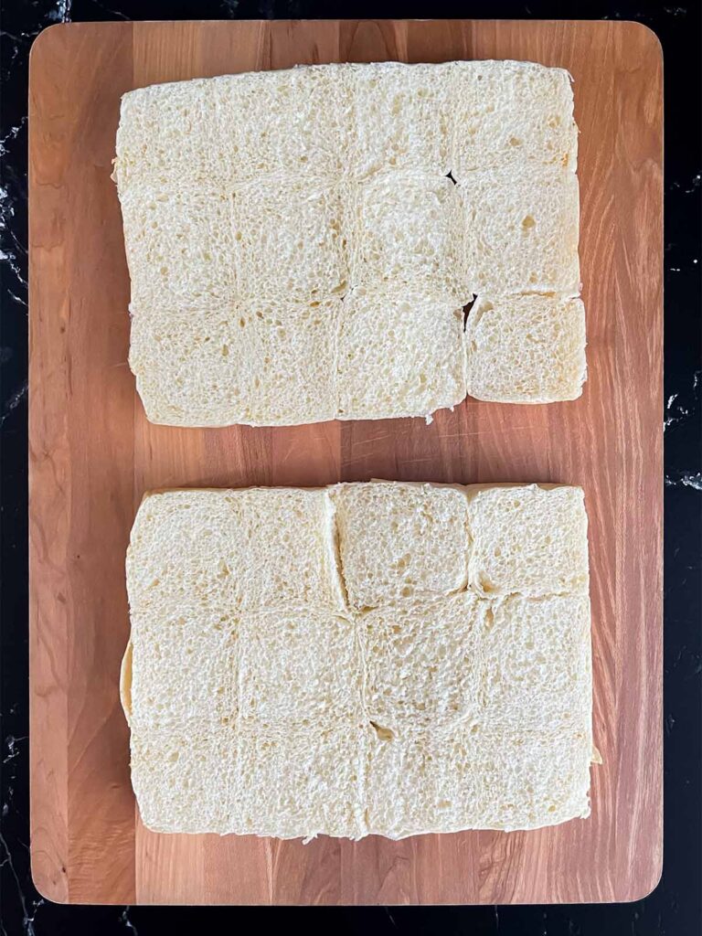 Slider buns cut on a wooden cutting board.