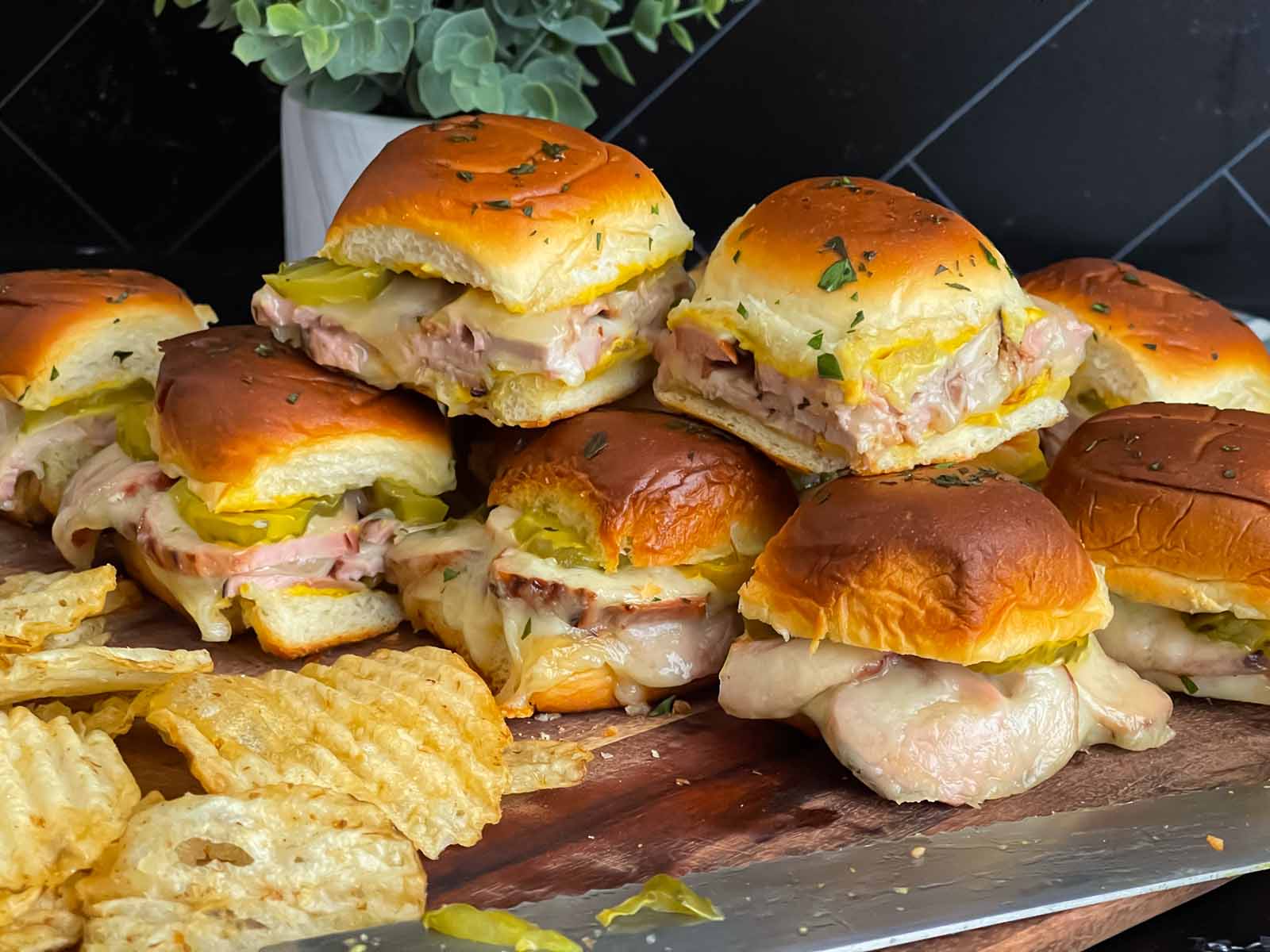 Cuban sliders stacked on a wooden board.