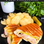 Grilled Cuban Pork Tenderloin Panini on a black plate with chips.