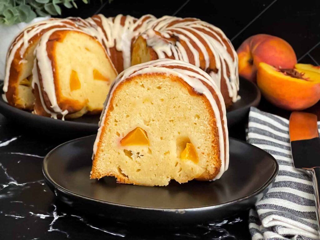 Peach pound cake on a dark plate on a dark surface.