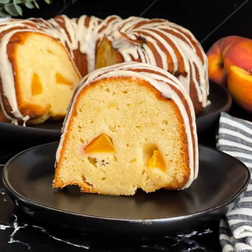 Peach pound cake on a dark plate on a dark surface.