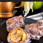 Apple fritters on a dark plate on a dark surface.