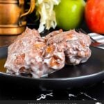 Apple fritters on a dark plate on a dark surface.