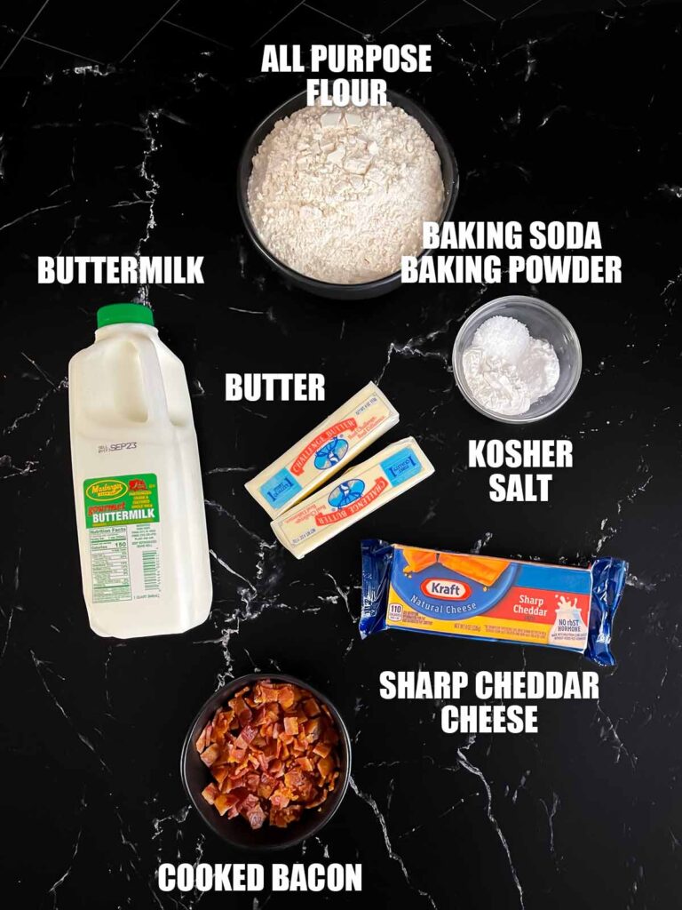 Bacon cheddar biscuits recipe ingredients on a dark surface.