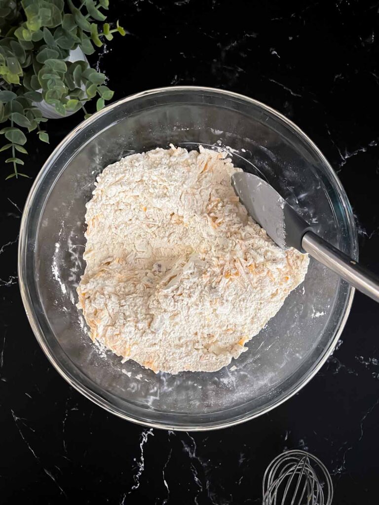 Shredded cheddar cheese stirred into the dry ingredients for bacon cheddar biscuits recipe.