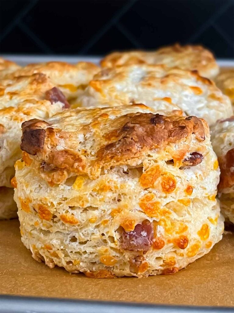 Baked bacon cheddar biscuits on a parchment lined baking sheet.