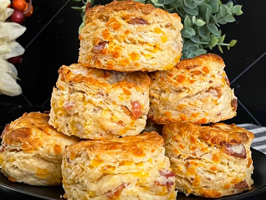 Bacon cheddar biscuits stacked on a dark plate.