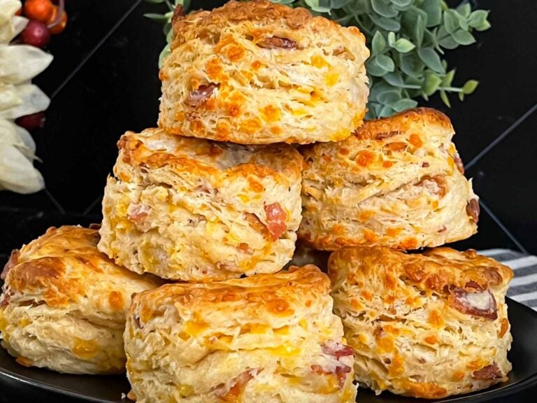 Bacon cheddar biscuits stacked on a dark plate.