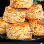 Bacon cheddar biscuits stacked on a dark plate.