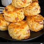 Bacon cheddar biscuits stacked on a dark plate.