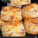 Bacon cheddar biscuits stacked on a dark plate.