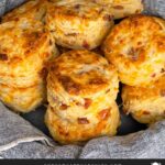 Bacon cheddar biscuits stacked in a towel lined bread basket.